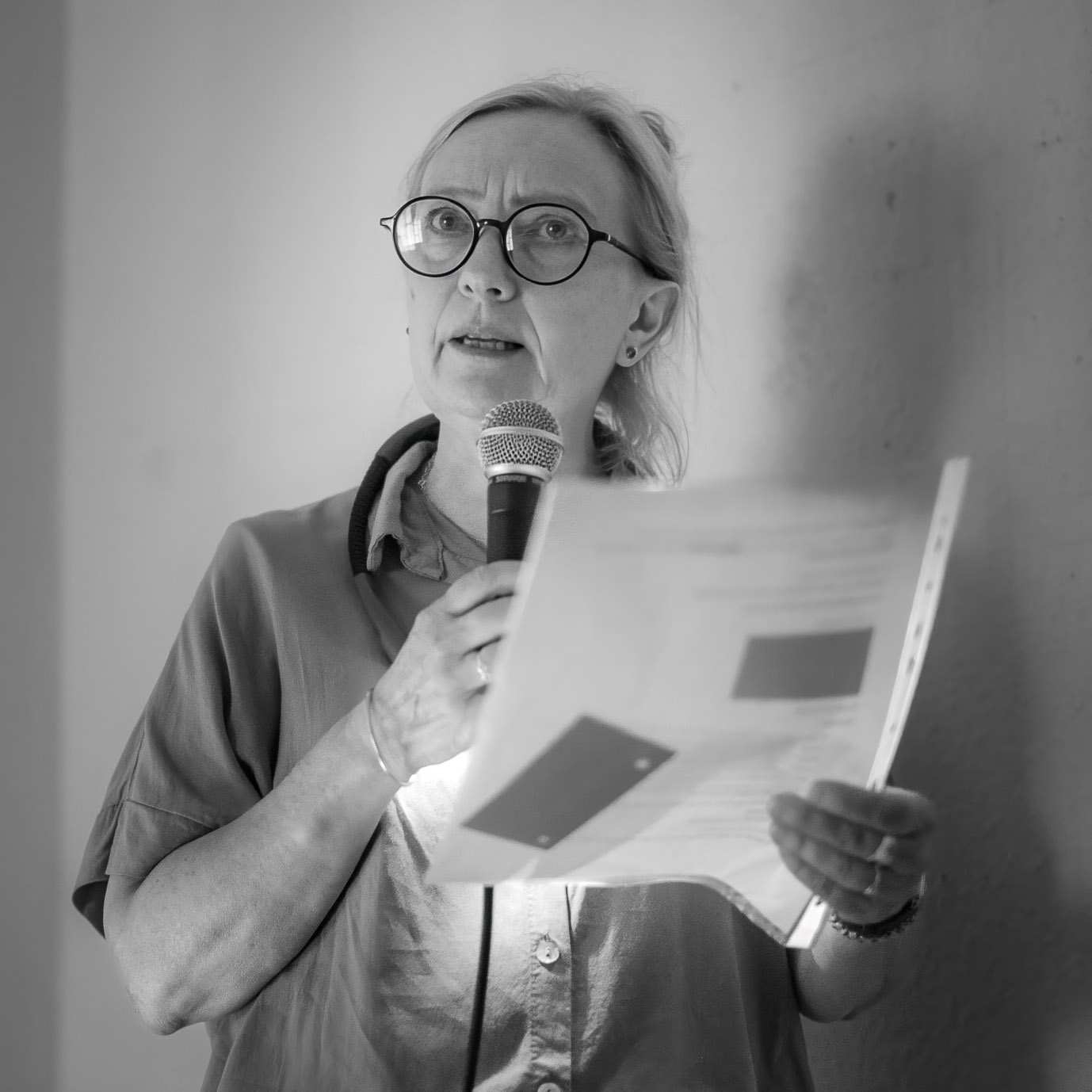 Eine Frau, die einen Text rezitiert. In der Hand hält sie das Skript.
